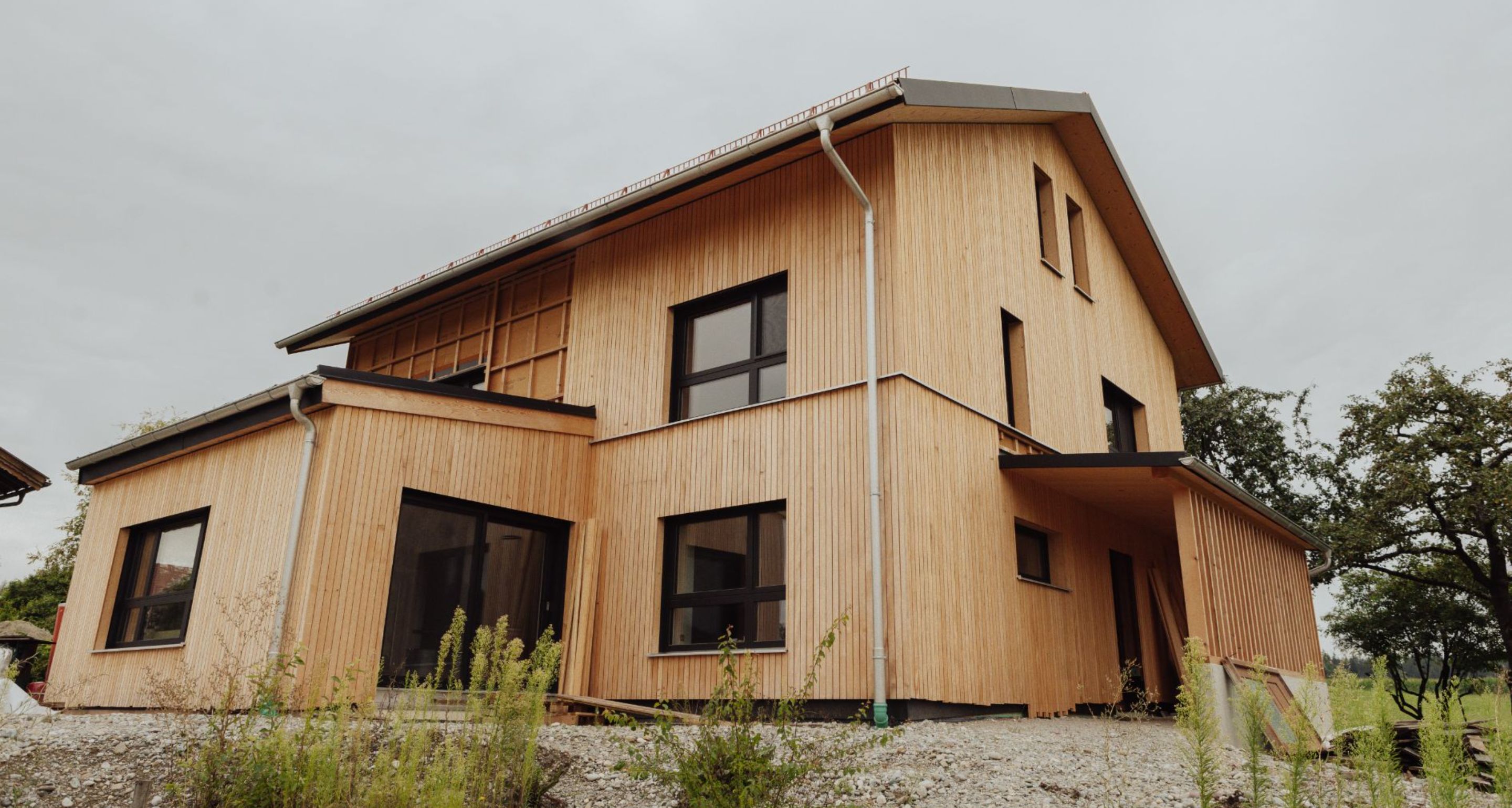 Modernes Wohnhaus mit vertikaler Fassade aus Weißtanne und schwarzen Fenstern