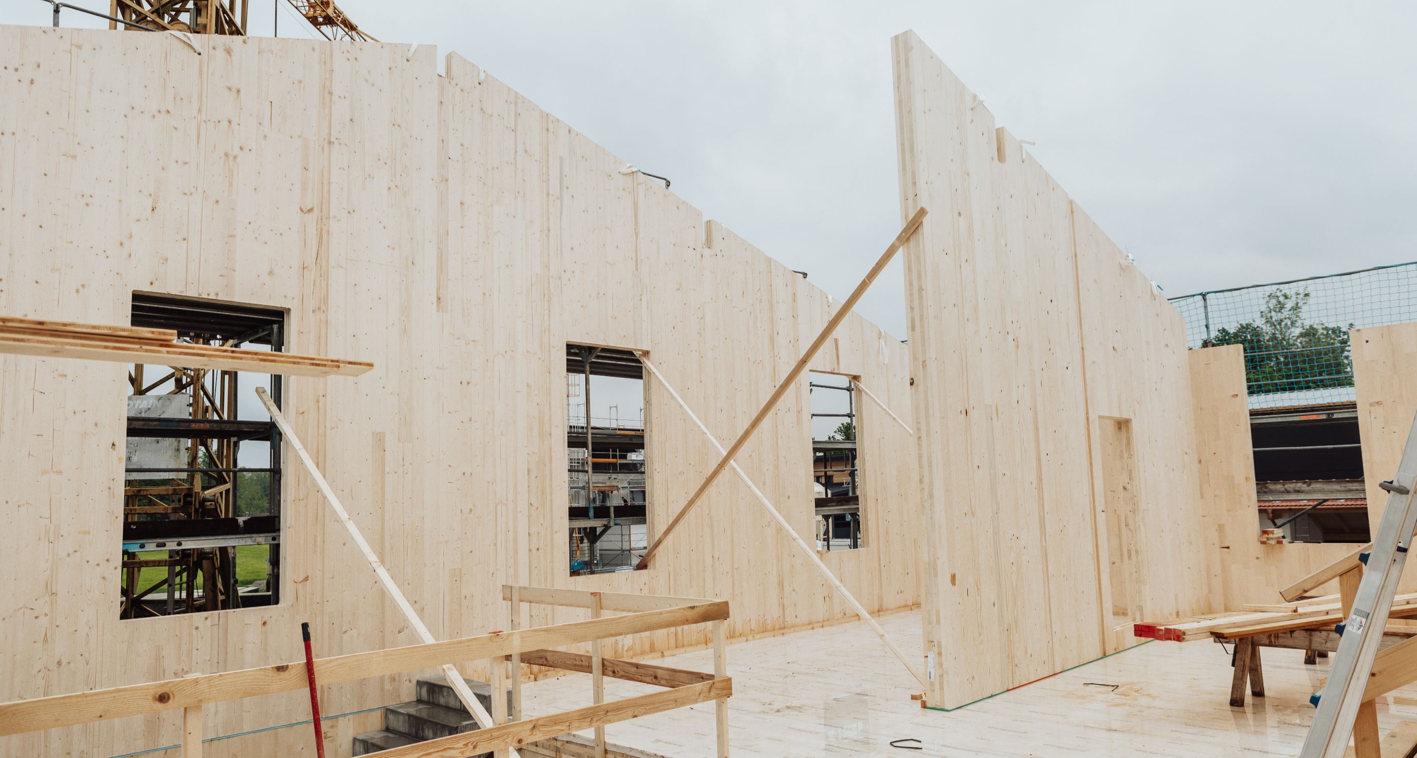 Montage von Brettsperrholz-Wänden (CLT) auf einer Baustelle für ein modernes Gewerbegebäude.