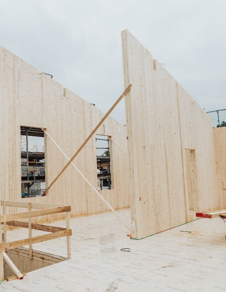 Montage von Brettsperrholz-Wänden (CLT) auf einer Baustelle für ein modernes Gewerbegebäude.