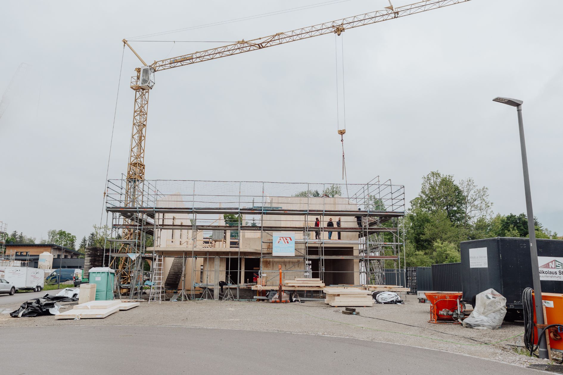 Baustelle eines Gewerbegebäudes in Holzbauweise mit Kran und Gerüst.