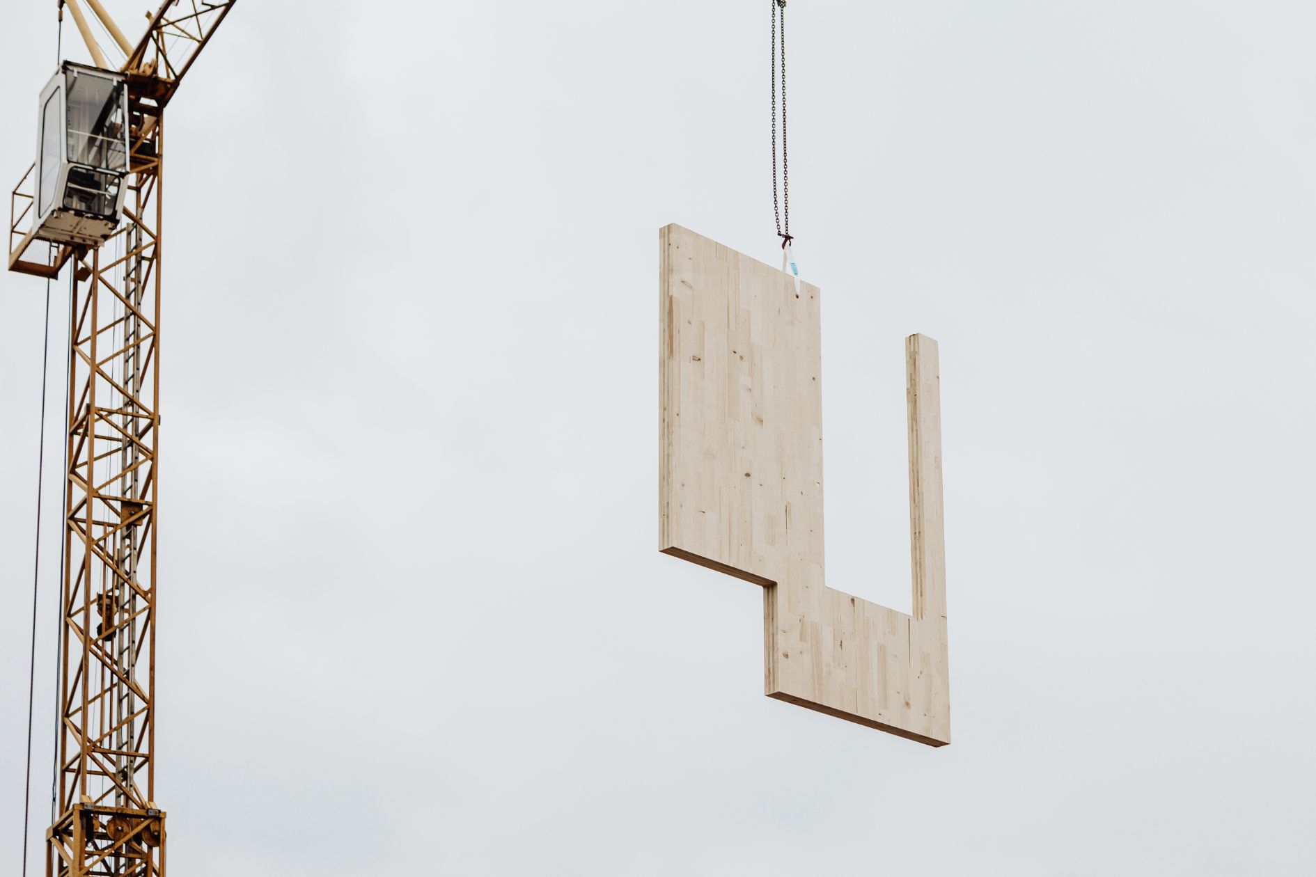 Kran hebt ein Brettsperrholz-Element (CLT) auf die Baustelle.