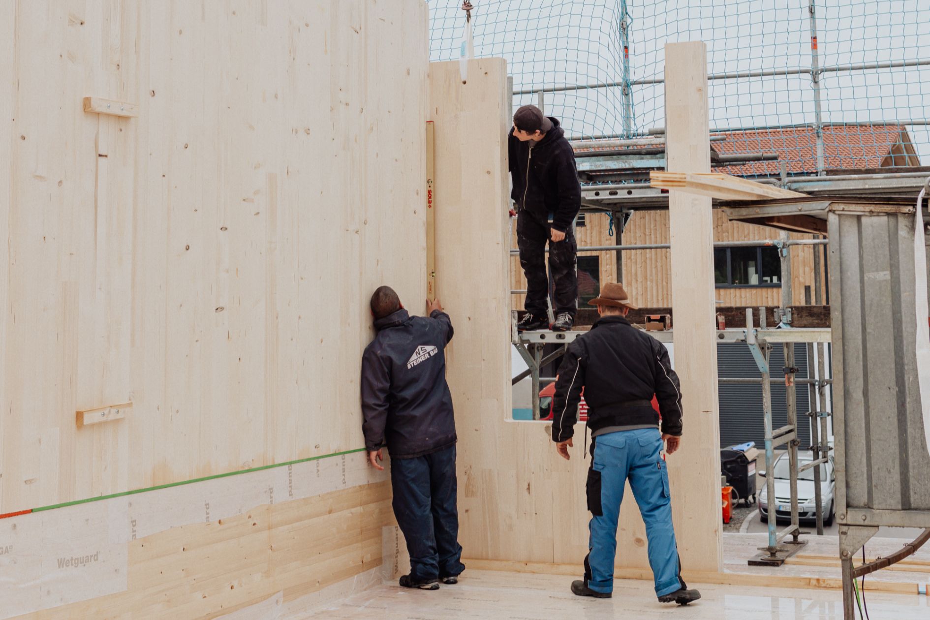 Handwerker montieren ein Brettsperrholz-Element (CLT) an der Wand.
