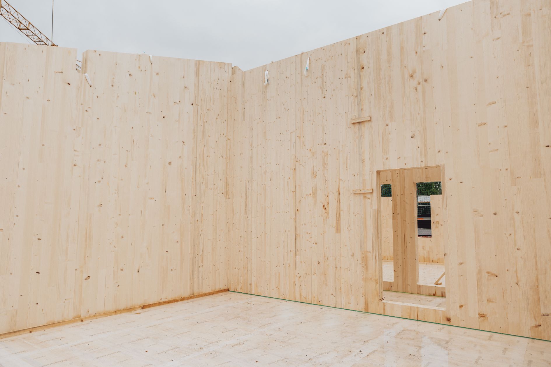 Innenansicht Rohbau mit Holz-CLT-Wänden und Türaussparung.