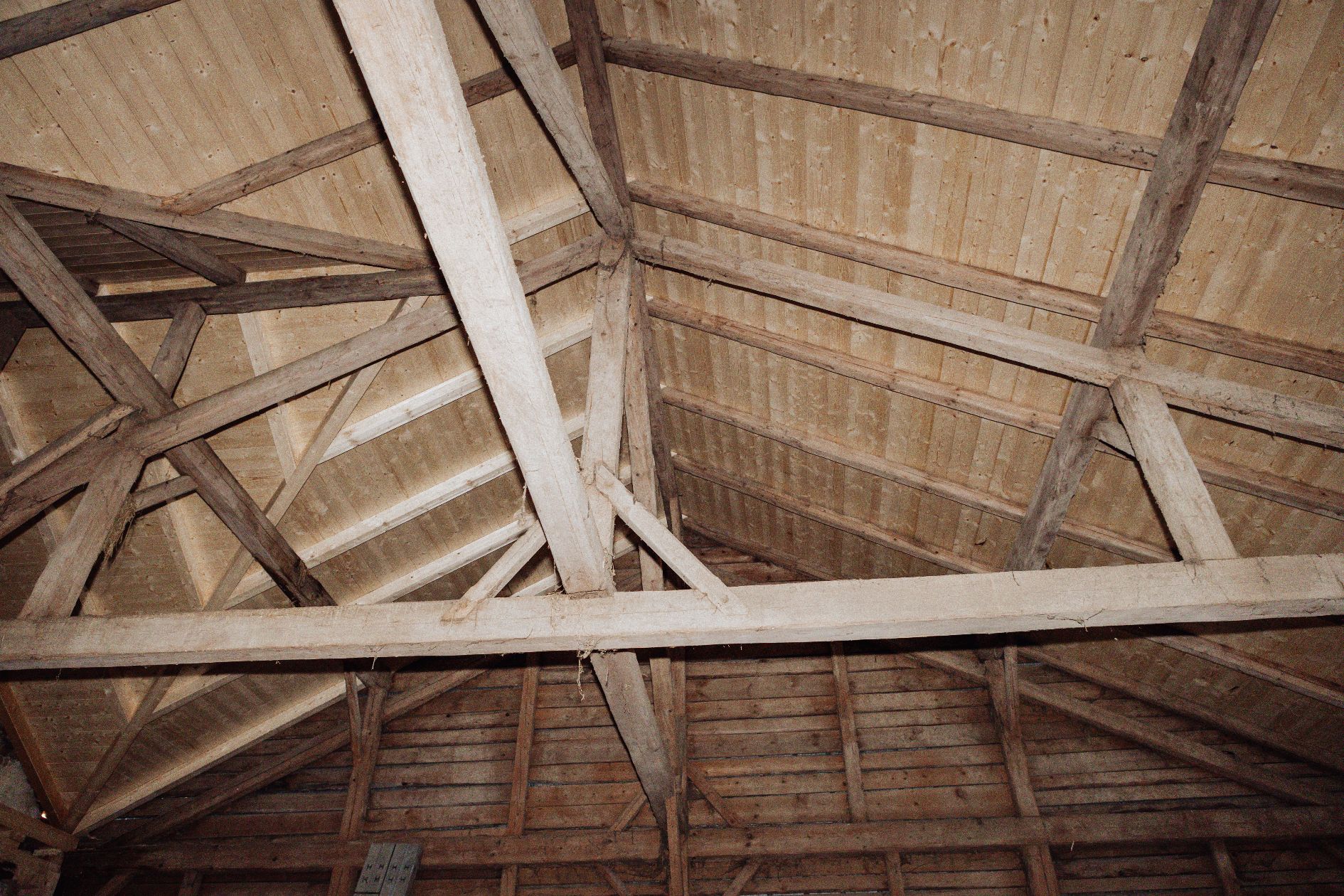 Historischer Dachstuhl mit sichtbarer Holzstruktur und moderner Schalung.