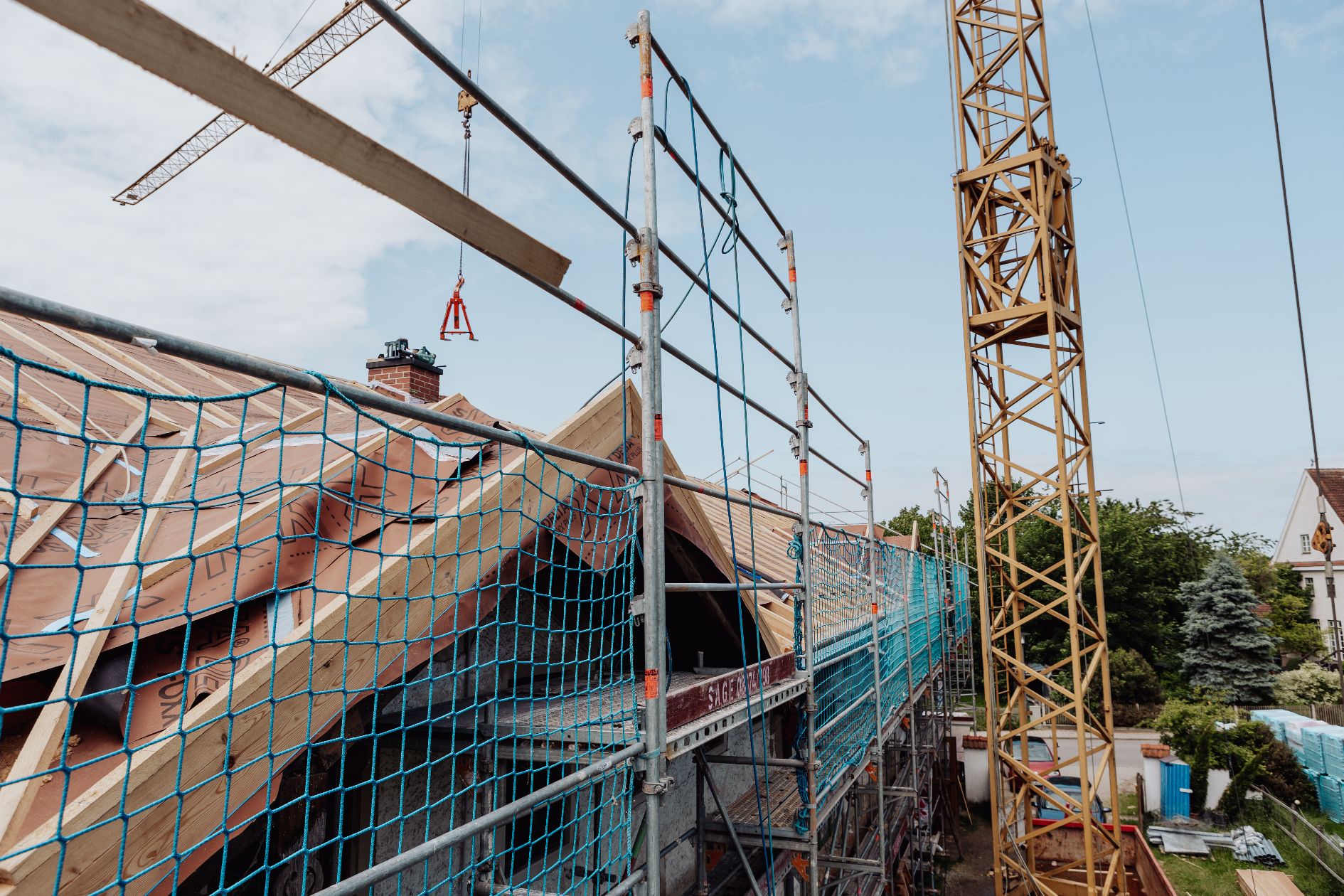 Neuer Dachstuhl im Bau mit Kran und Baugerüst.