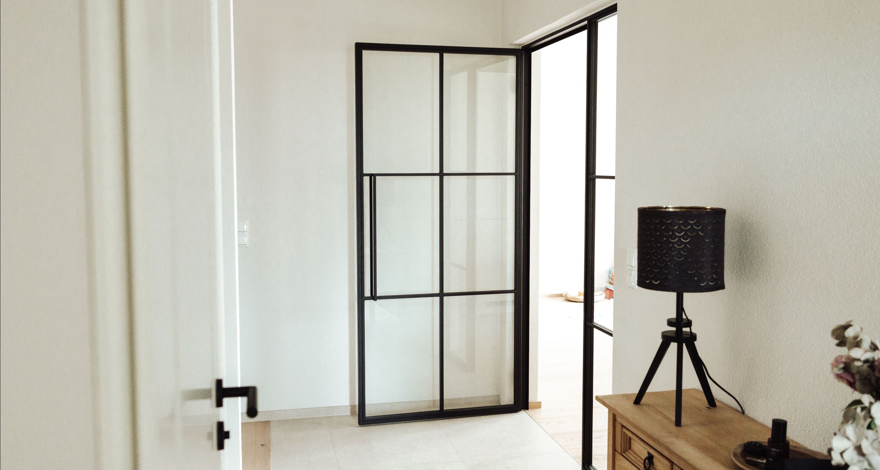 Lofttüre aus schwarzem Stahl mit Glaselementen, modern eingebaut im Wohnraum.