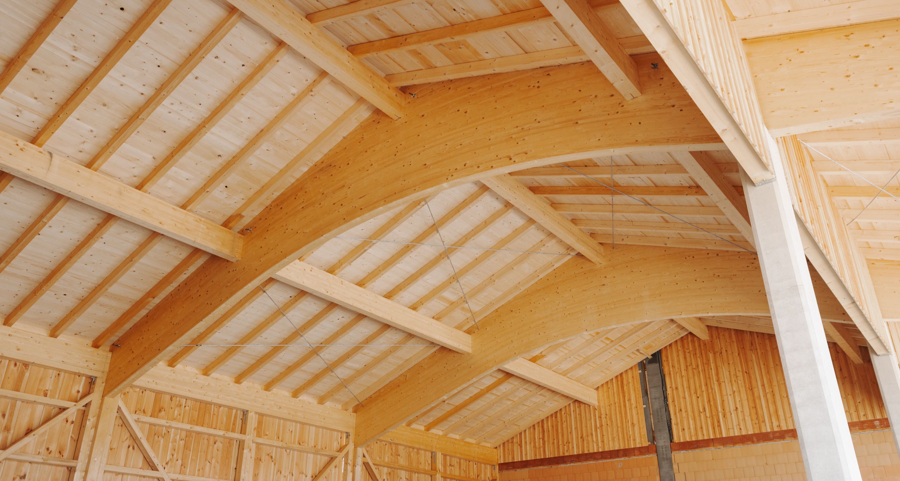 Holzbau mit eindrucksvollen Bogenbindern im Dachstuhl.