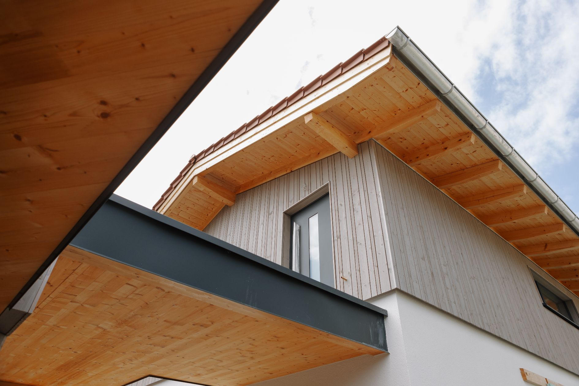 Detailaufnahme Holzfassade mit Fenster und Dach.