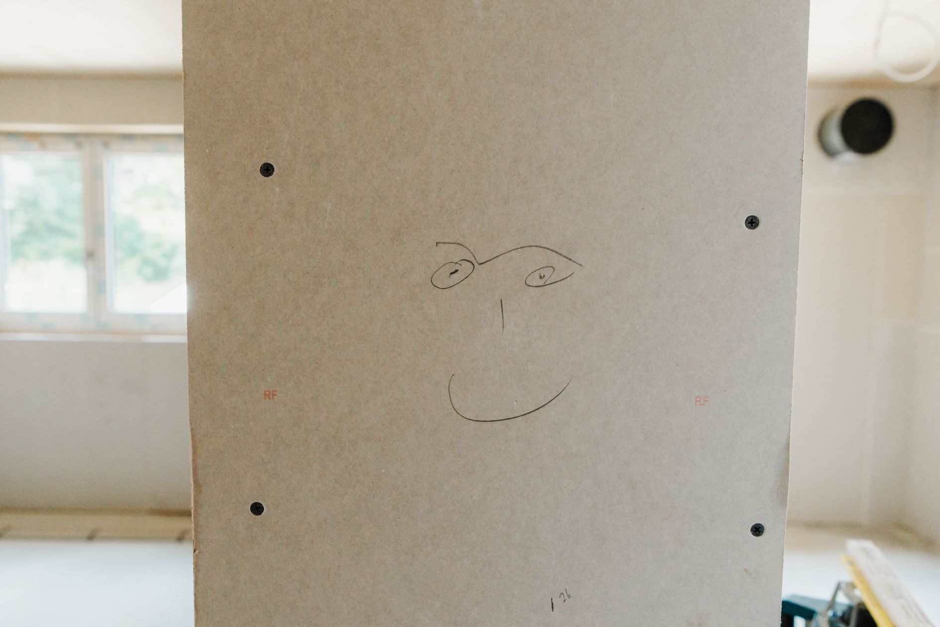 Smiley-Zeichnung auf Rigipswand im Neubau.