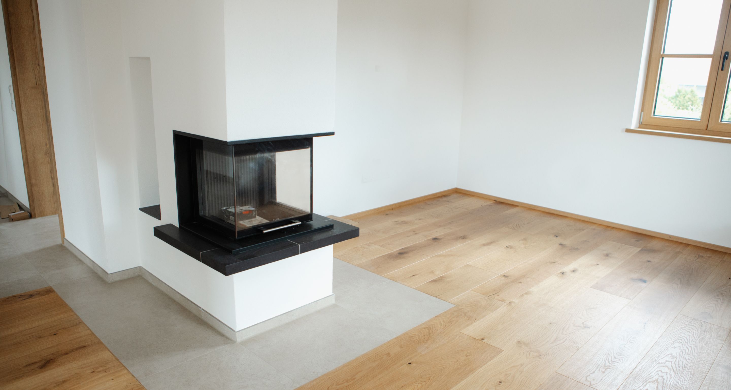 Wohnraum mit Kamin, Eichenparkett und Fliesenübergang.