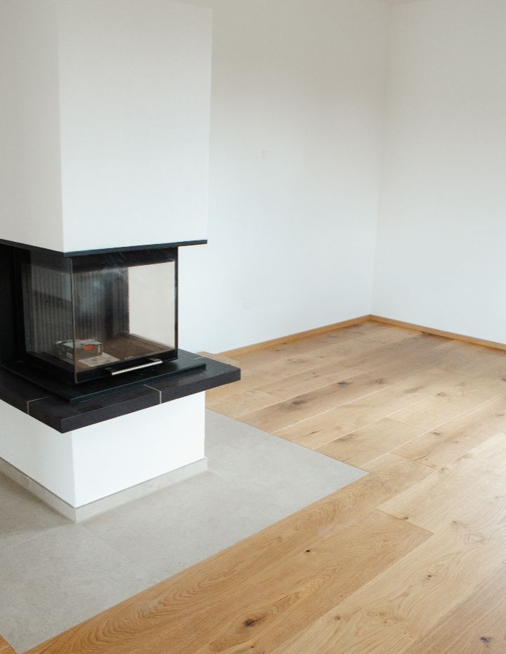 Wohnraum mit Kamin, Eichenparkett und Fliesenübergang.
