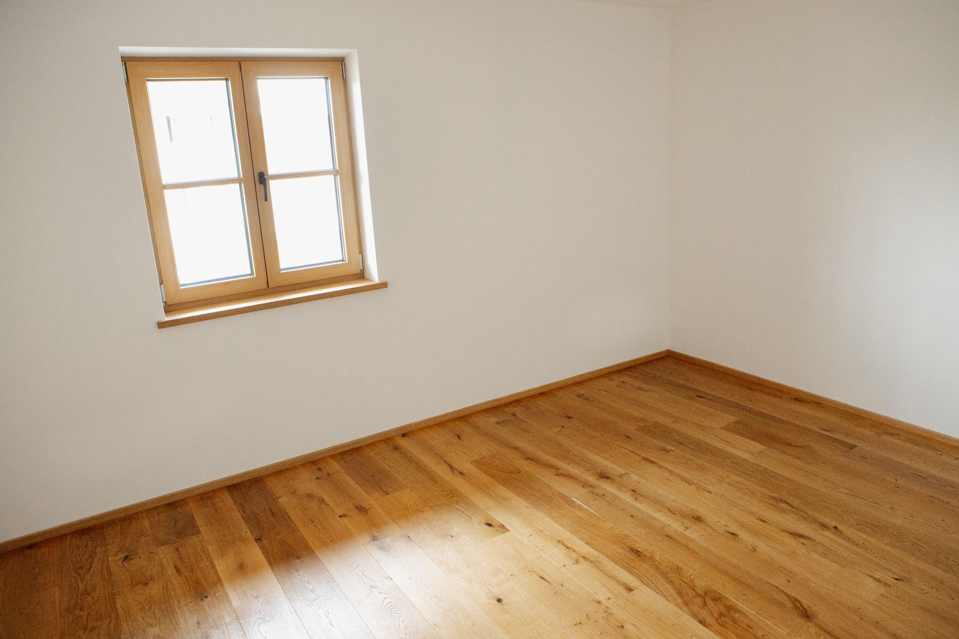 Zimmer mit Fenster und Parkett – heller Raum mit Eiche-Boden und Holzfenster.
