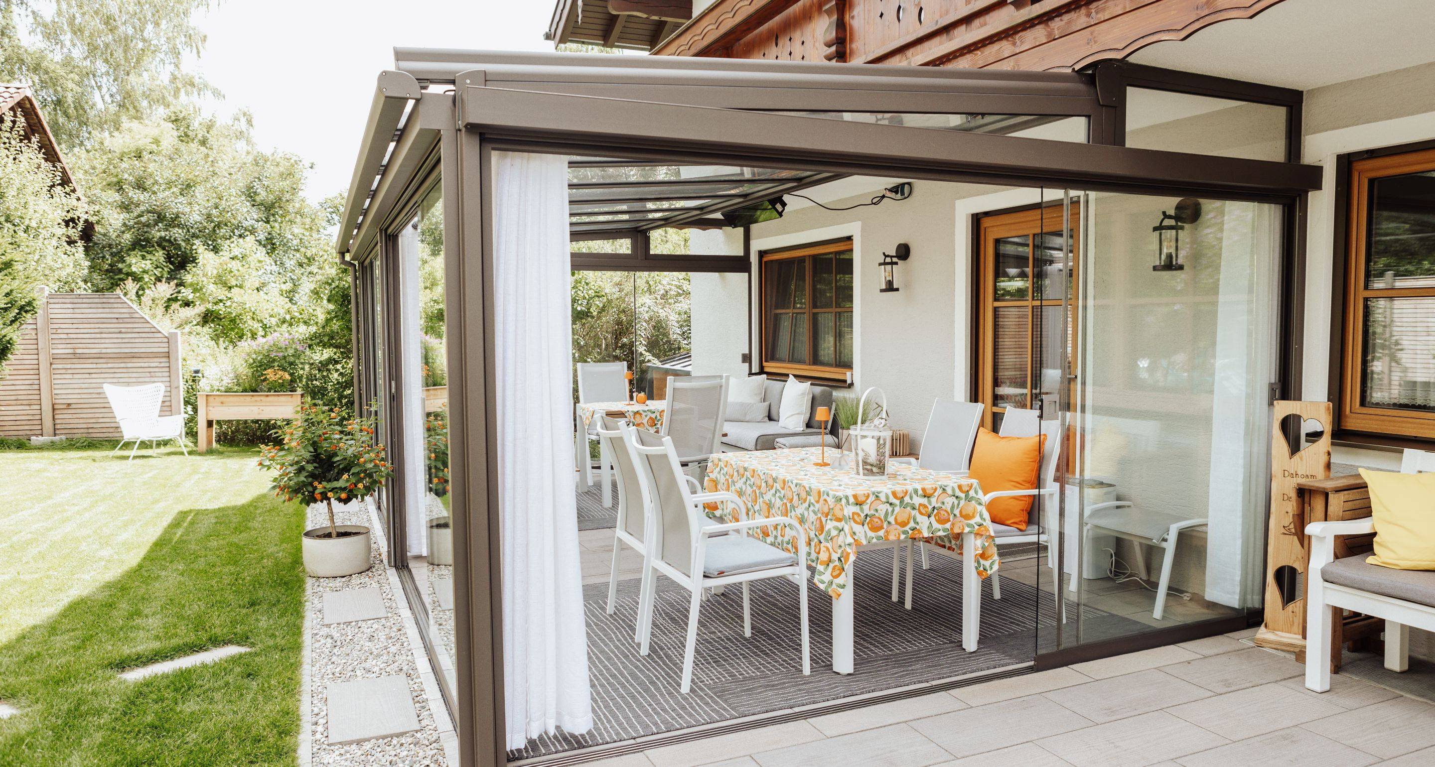 Überdachte Terrasse mit Glaswänden und Sitzbereich.