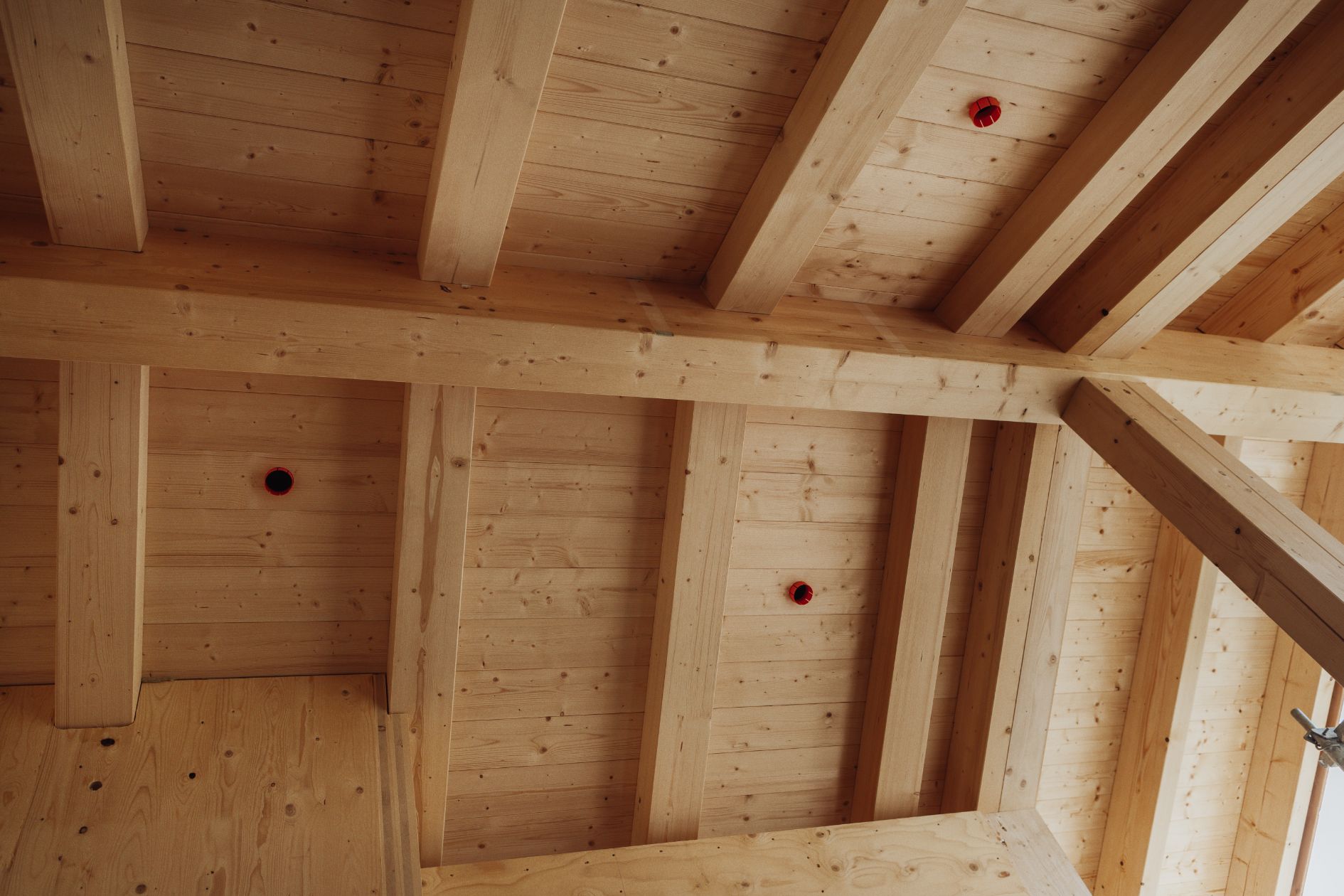 Detailansicht einer Holzdecke mit sichtbaren Brettschichtholzträgern und Brettsperrholzflächen