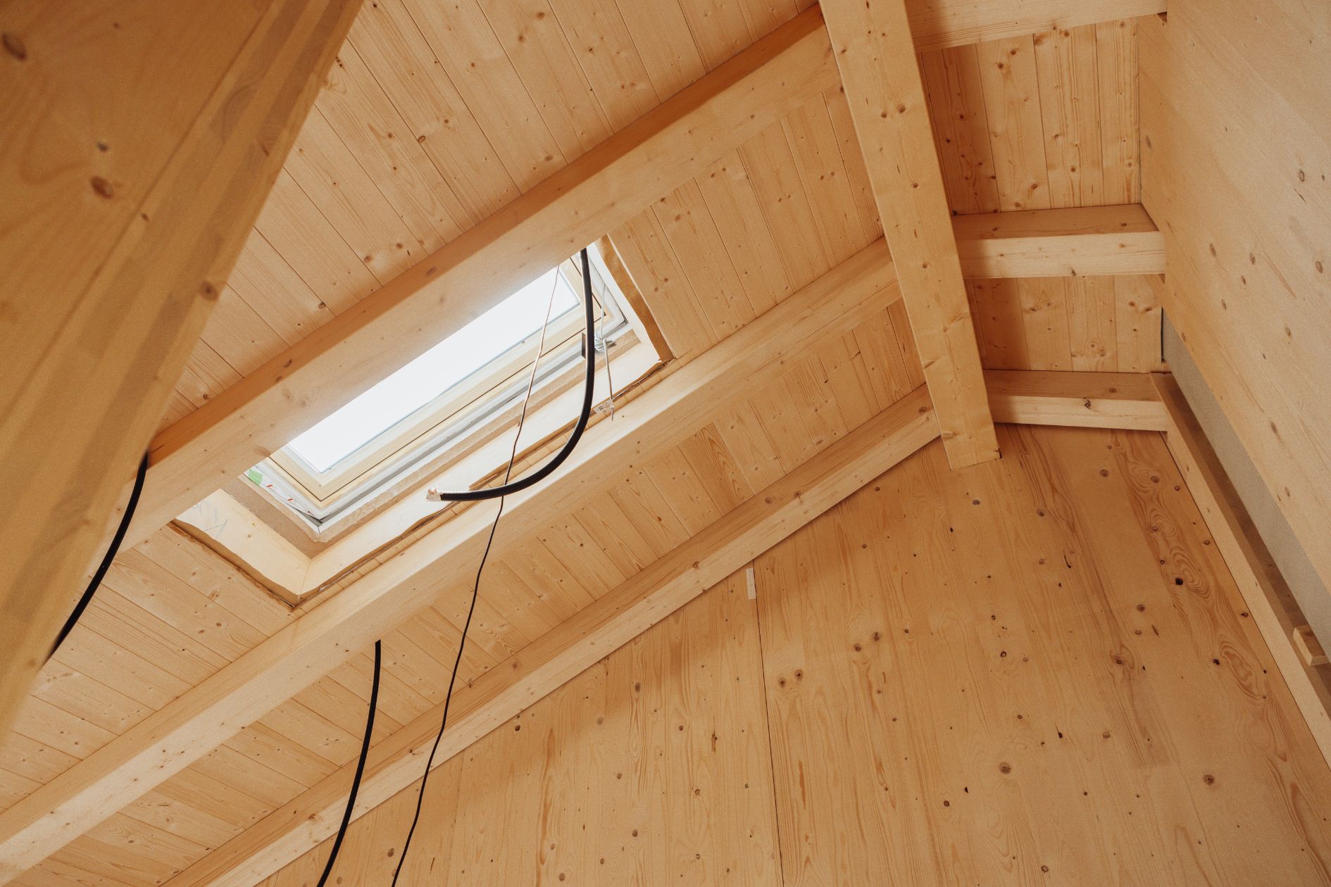 Innenansicht eines Dachstuhls aus Brettsperrholz mit eingebautem Dachfenster