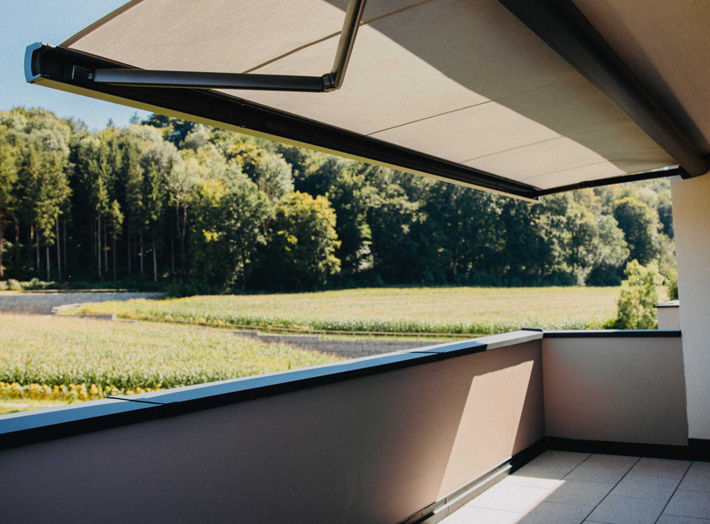 Terrasse mit Markise und Blick auf Feld und Wald
