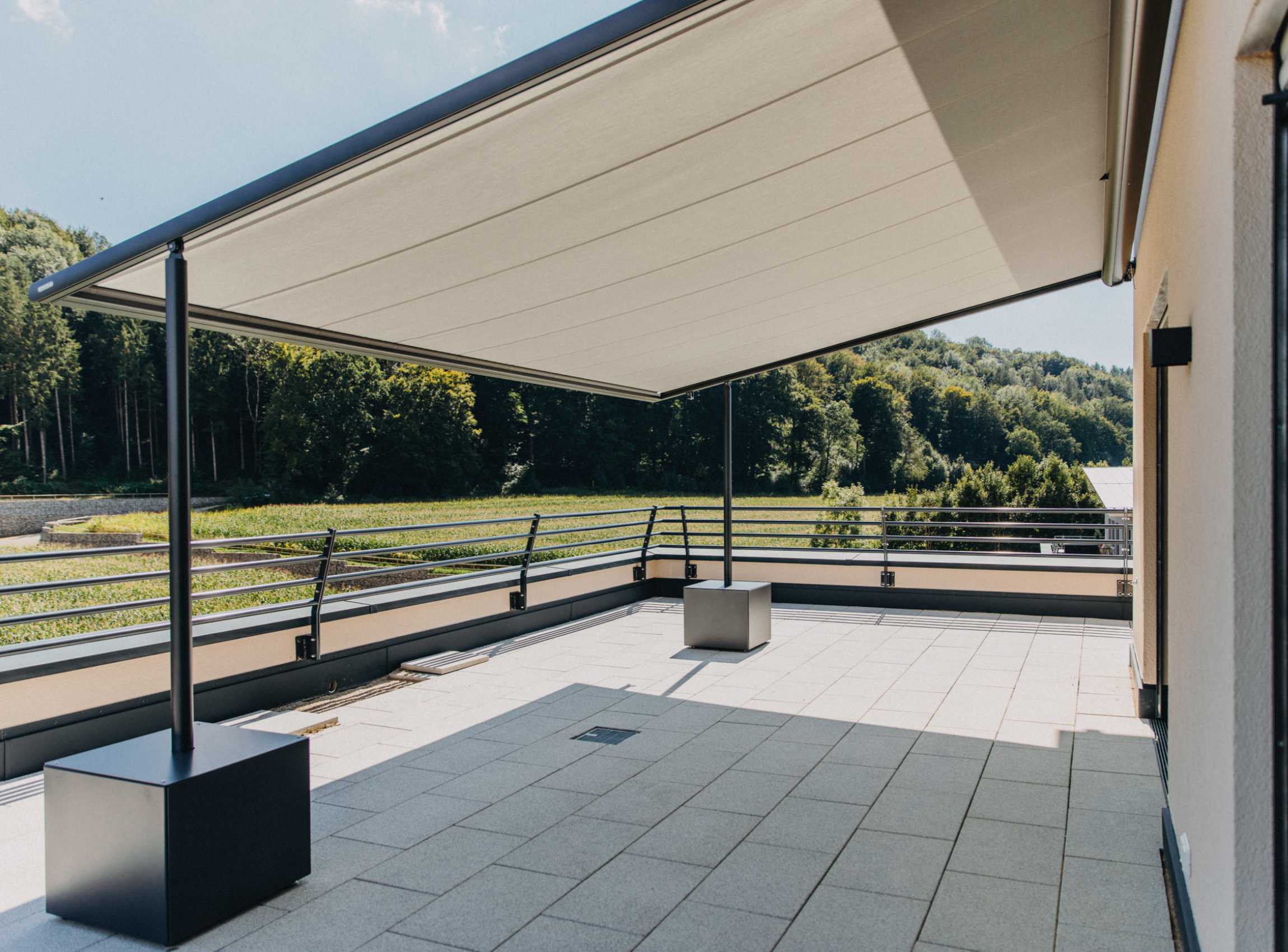 Dachterrasse mit großflächiger Markise und Blick auf grüne Landschaft – moderne Klarheit trifft Naturverbundenheit