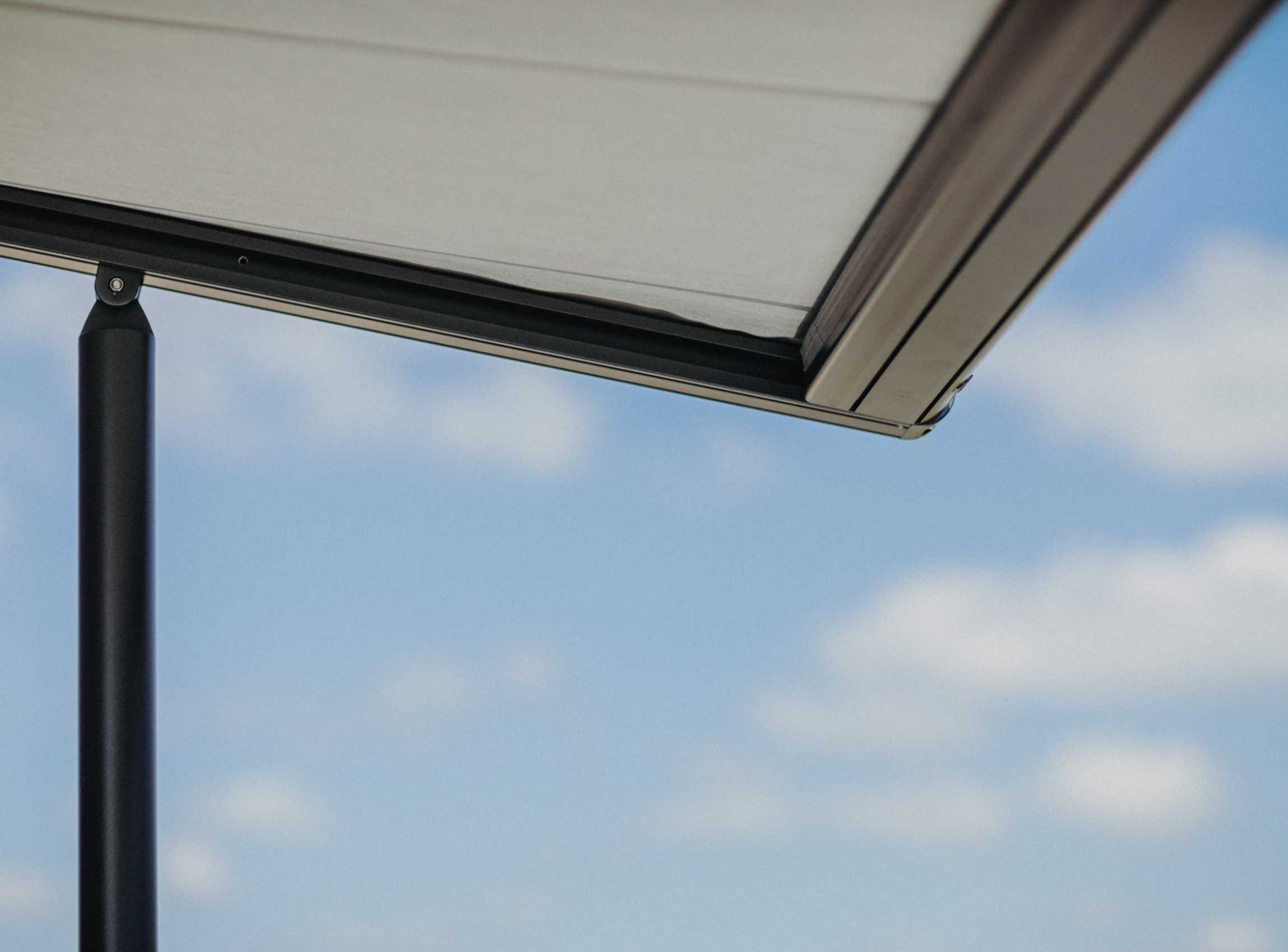 Detailaufnahme einer Markise vor blauem Himmel – klare Technik trifft auf reduziertes Design