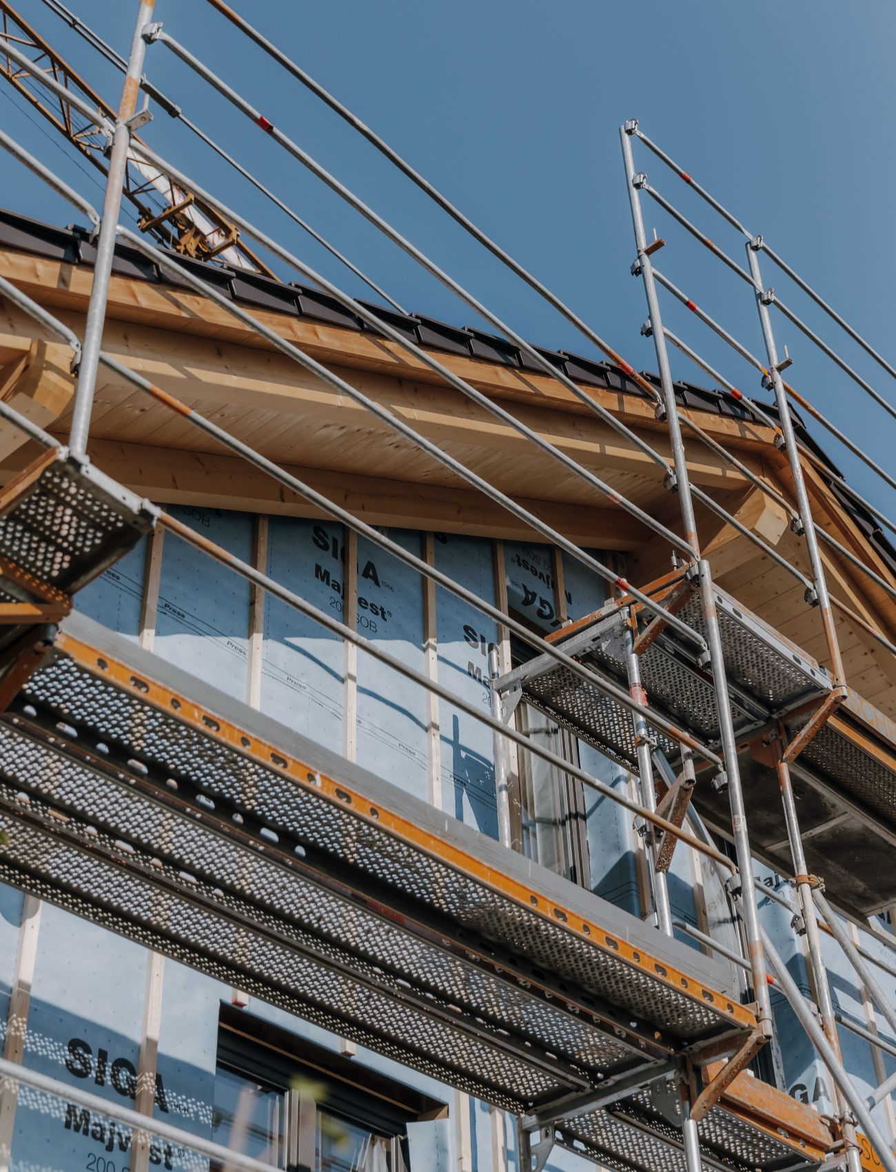 Hausfassade mit blauer Dämmung, Holzgiebel und Baugerüst