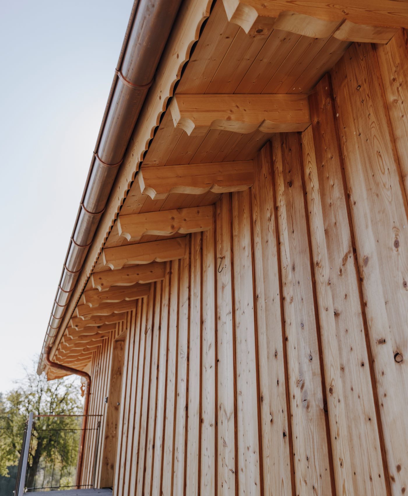 Nahaufnahme einer hölzernen Hausfassade mit Dachüberstand und Kupferregenrinne