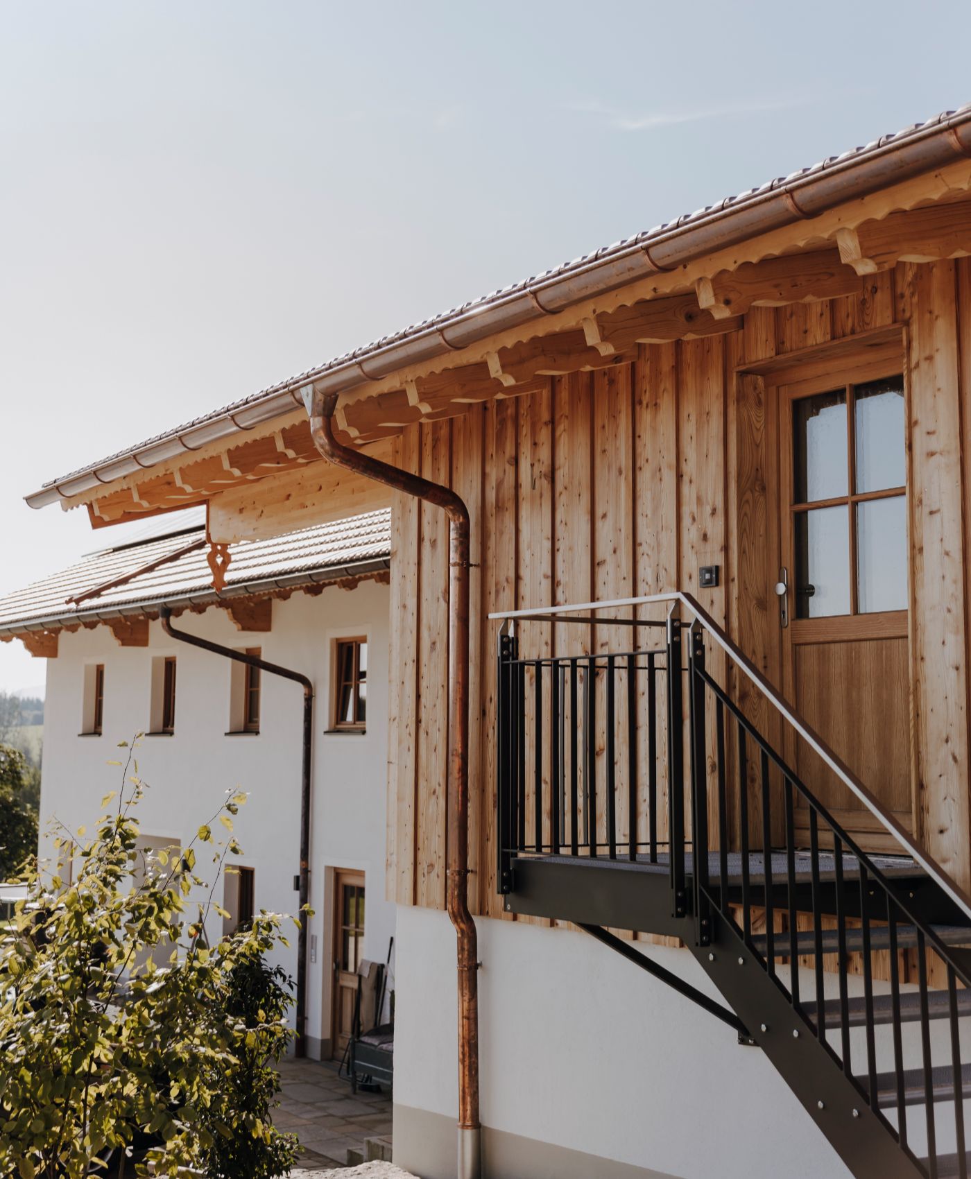 Wohnhaus mit Holzfassade, Außentreppe aus Metall und Kupferregenrinne