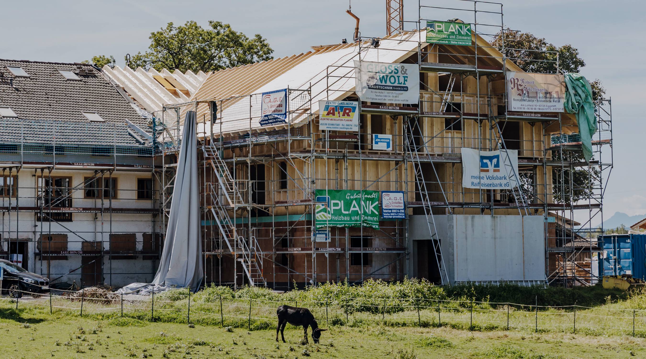 Baustelle eines Hotels mit Gerüst und Firmenschildern,