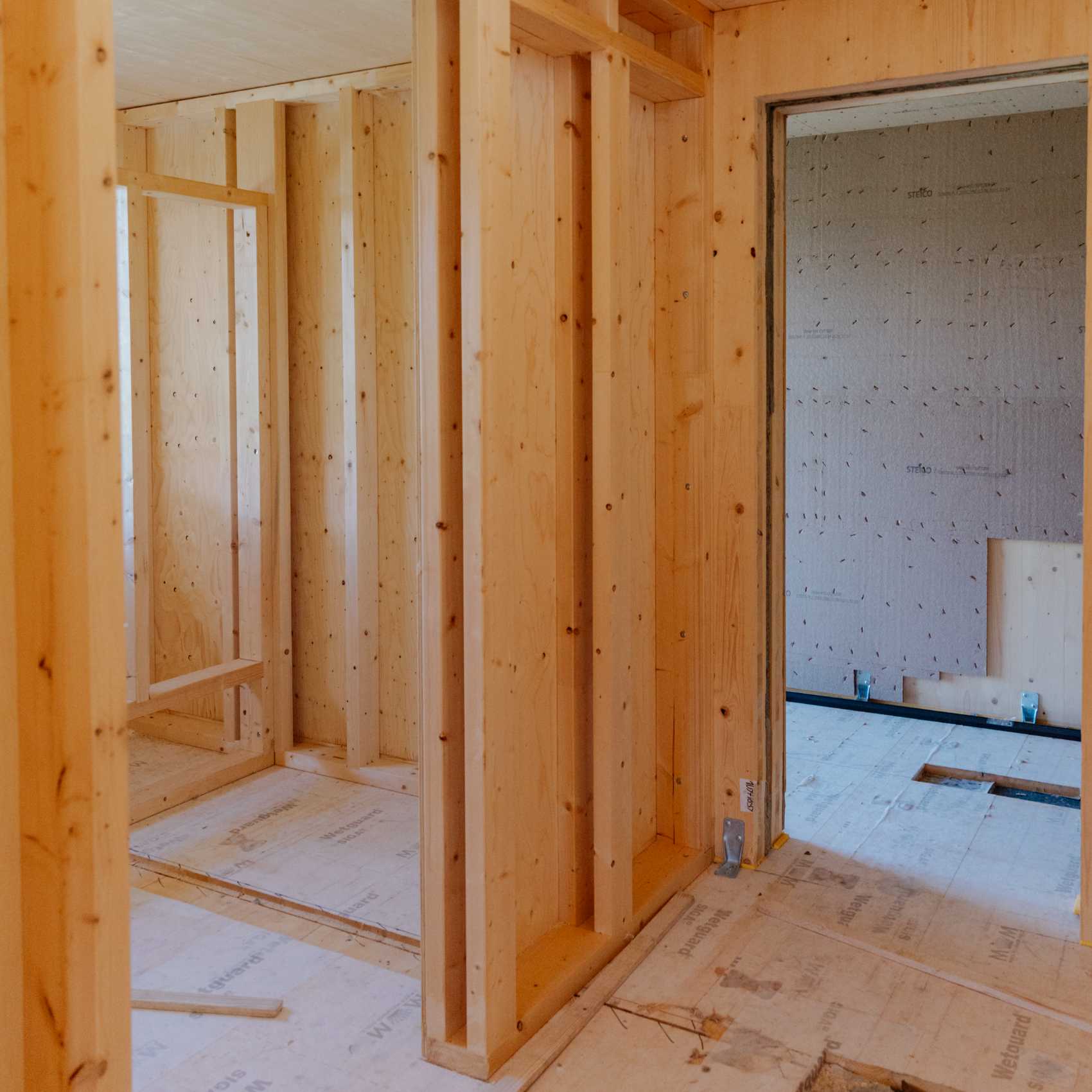 Innenansicht eines Holzrahmenbaus mit offenen Wänden und sichtbaren Holzständern