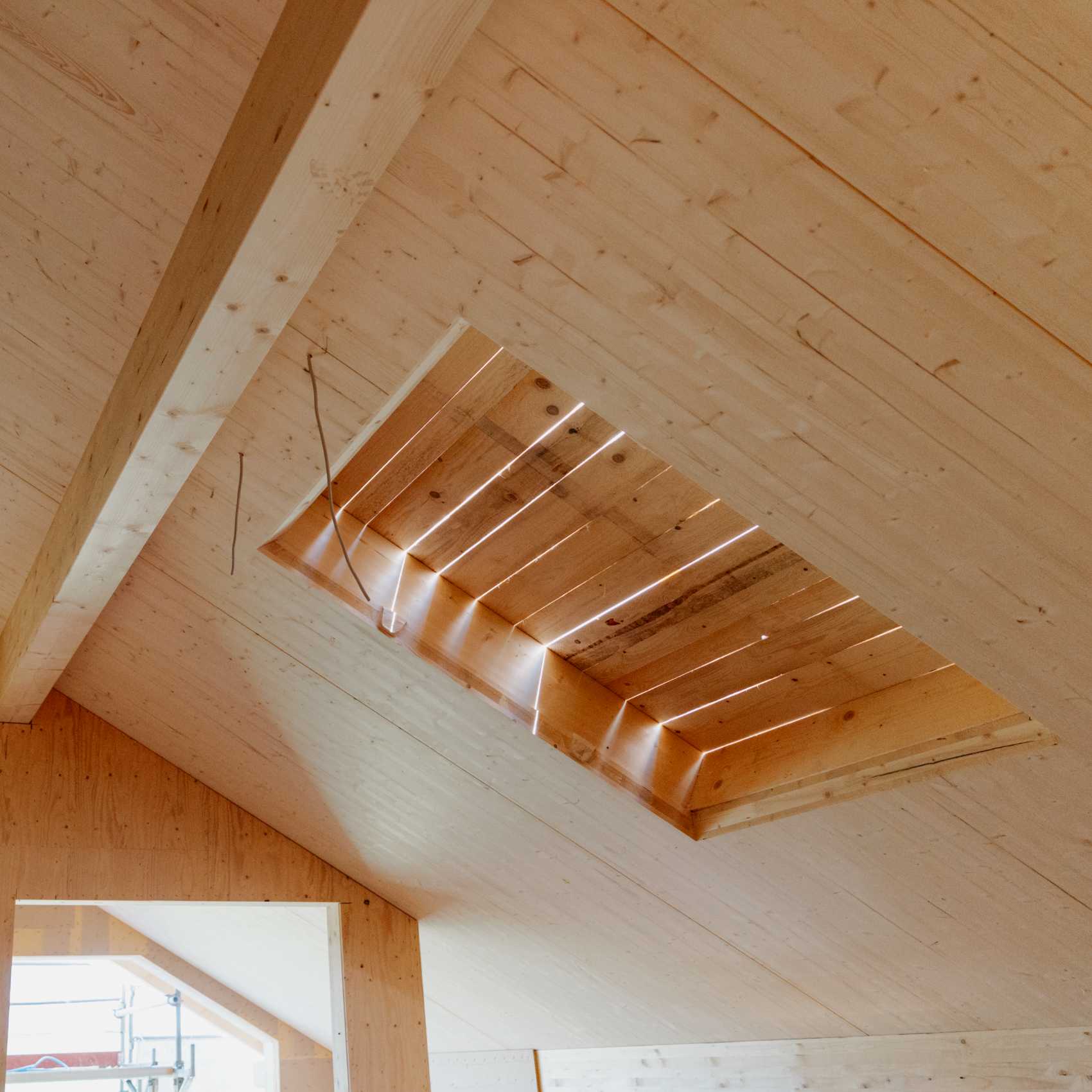 Holzdecke eines Neubaus mit rechteckiger Öffnung für ein Dachfenster,