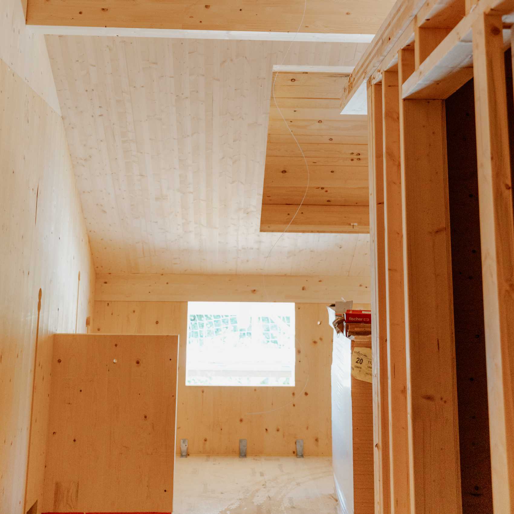 Innenraum eines Neubaus mit Holzverkleidung, sichtbarem Fenster und vorbereiteter Deckenöffnung