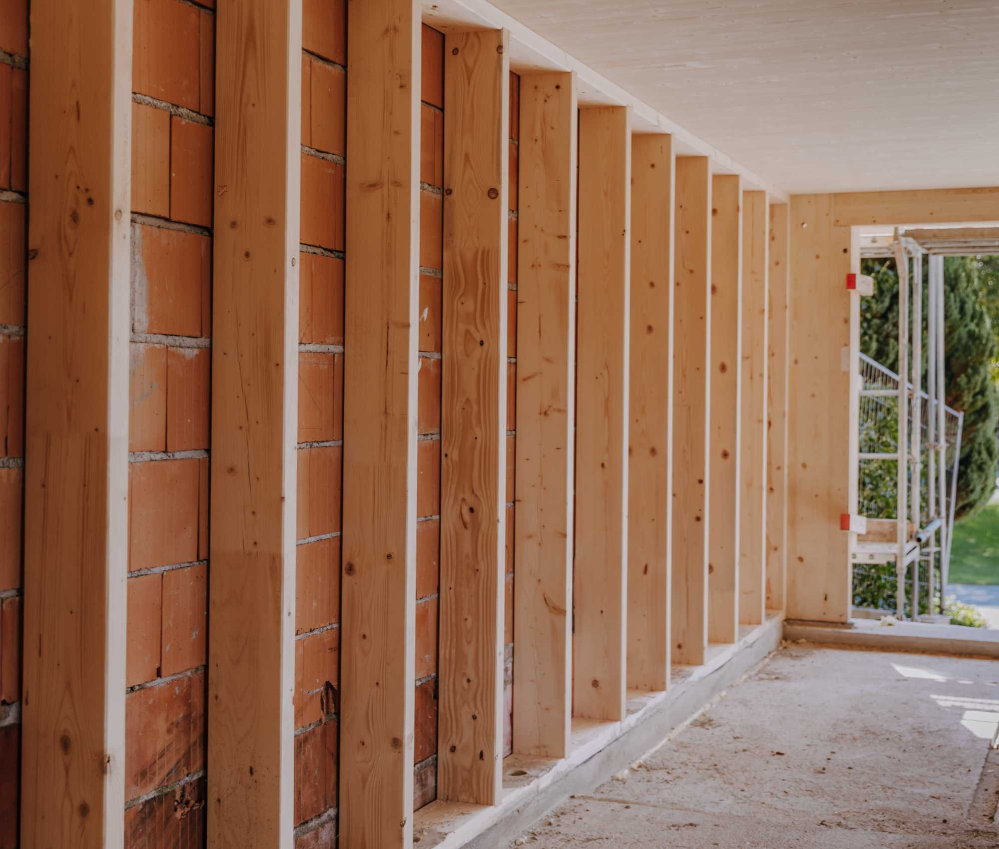 Baustellenansicht eines Gebäudes mit unverputzter Ziegelwand und Holzständerkonstruktion