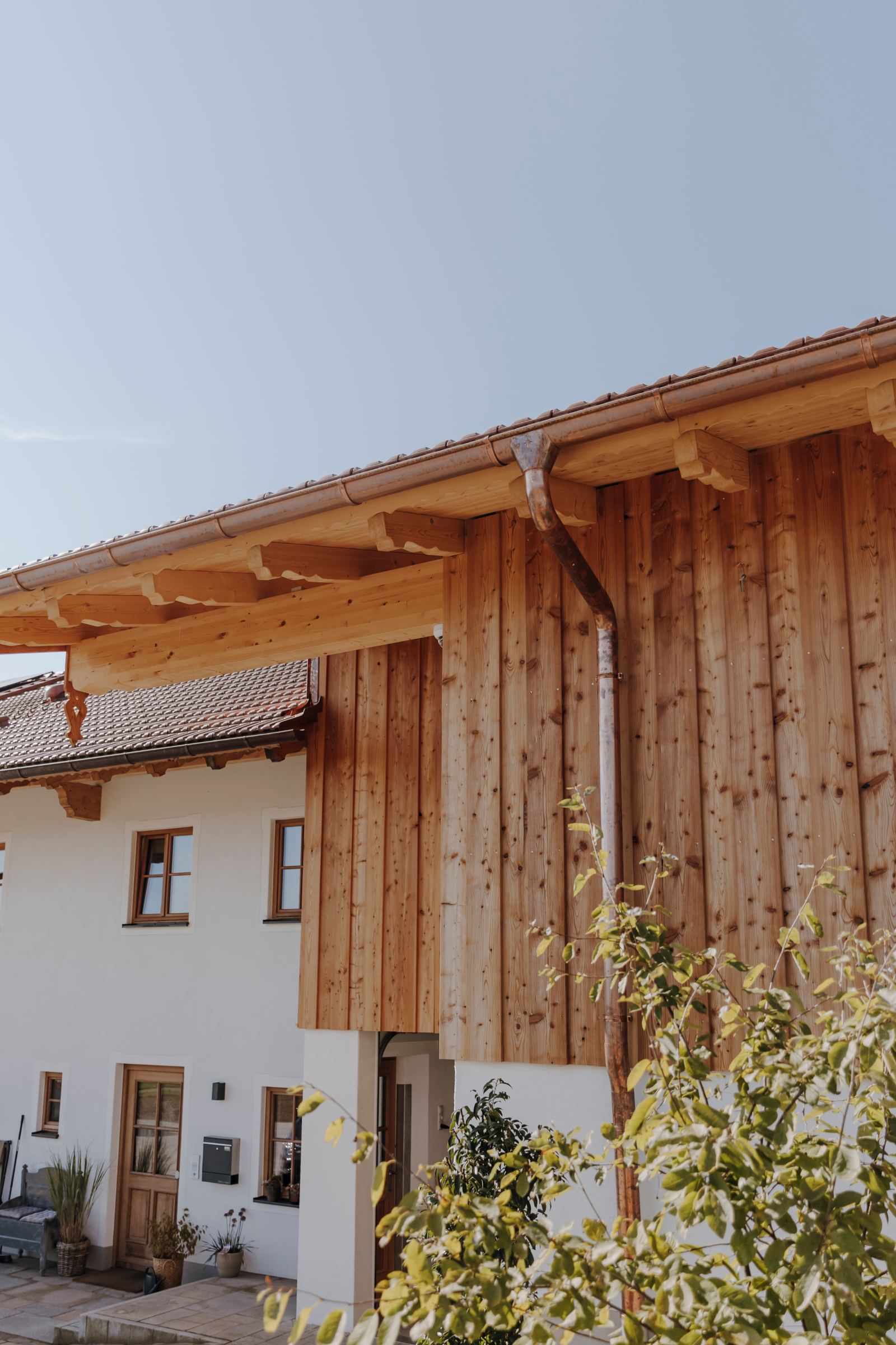 Fassade eines Hauses mit Holzverkleidung und sichtbarer Regenrinne