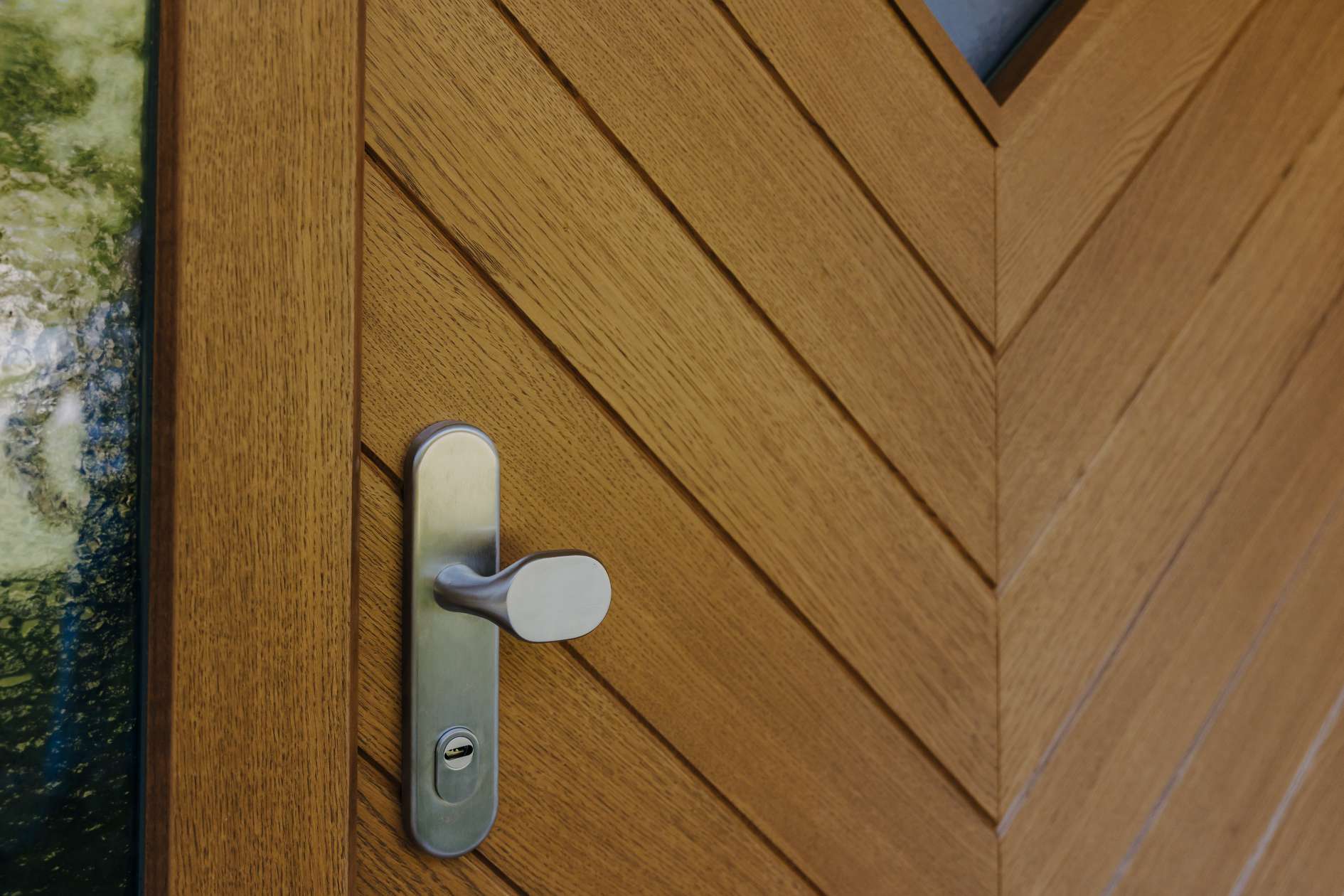 Metalltürgriff auf Holztür mit diagonaler Maserung.