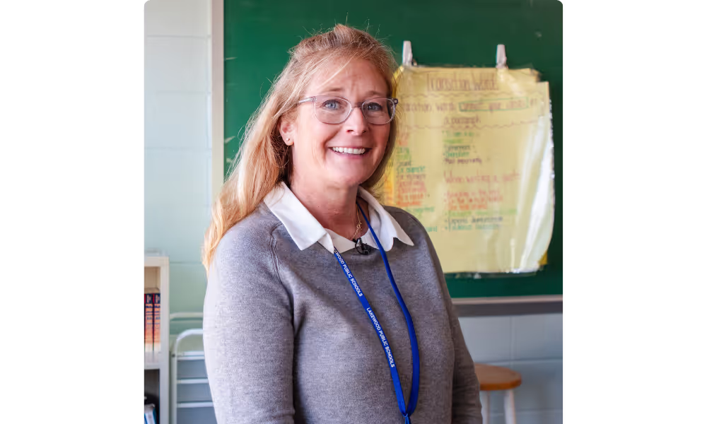 A teacher smiling in front of a chalkboard