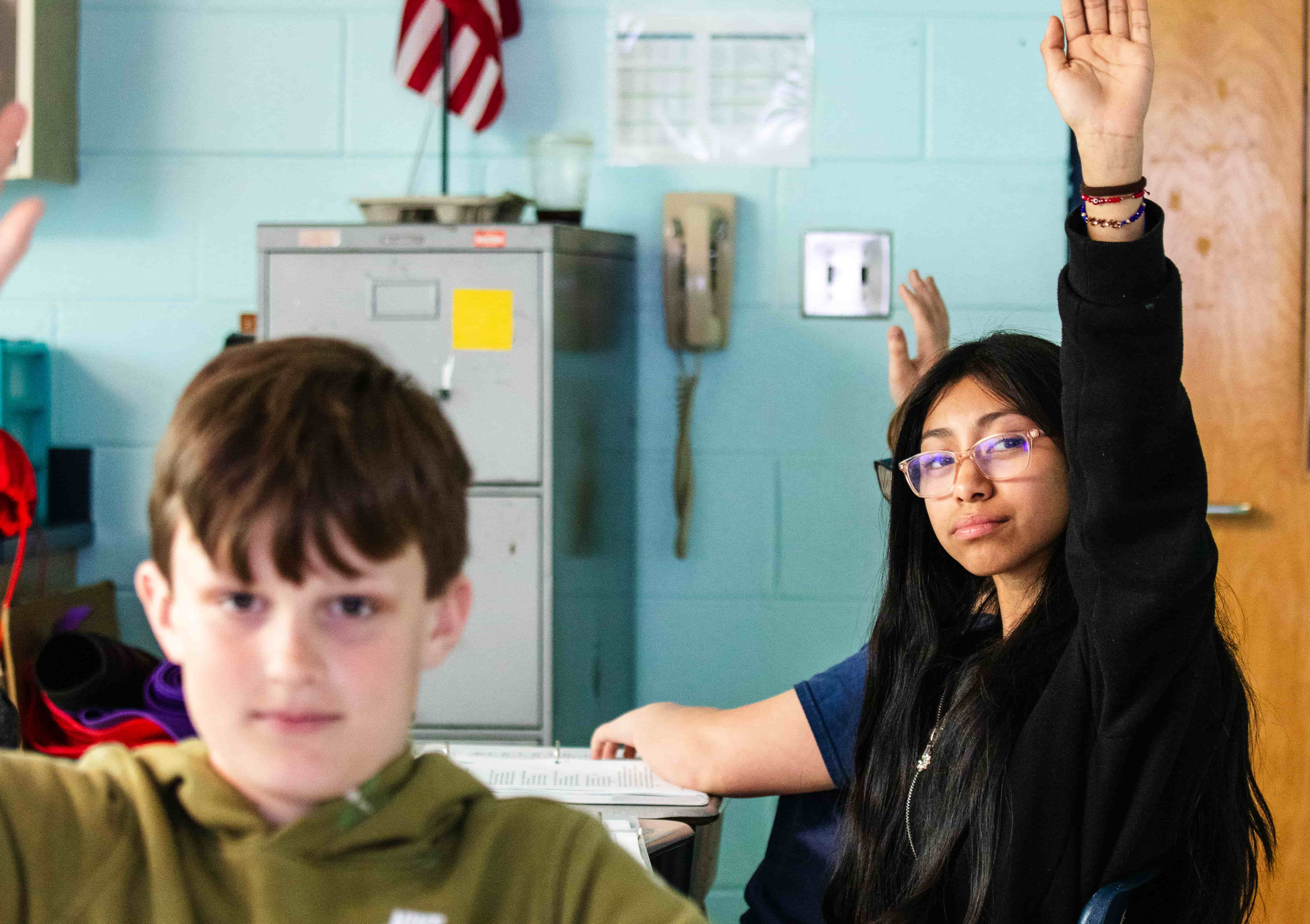 Photograph of student in a classroom raising her hand