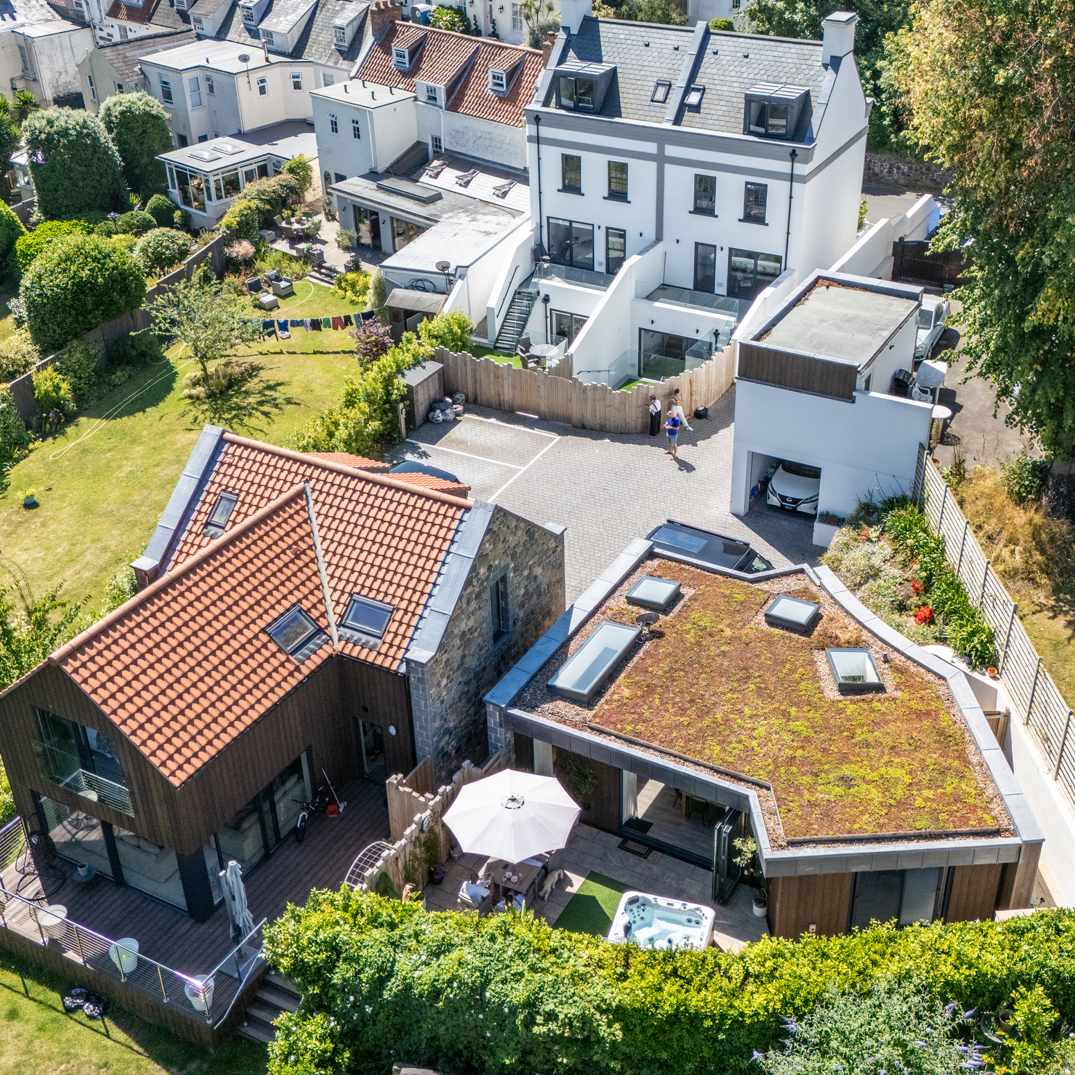 Aerial view of modern homes with green roof, stone and timber facades, red-tiled roof, landscaped gardens and courtyard space