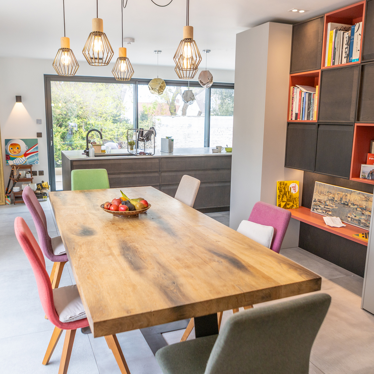 Modern open-plan living space with soft lighting, pendant lamps, and visible dining, lounge and kitchen zones