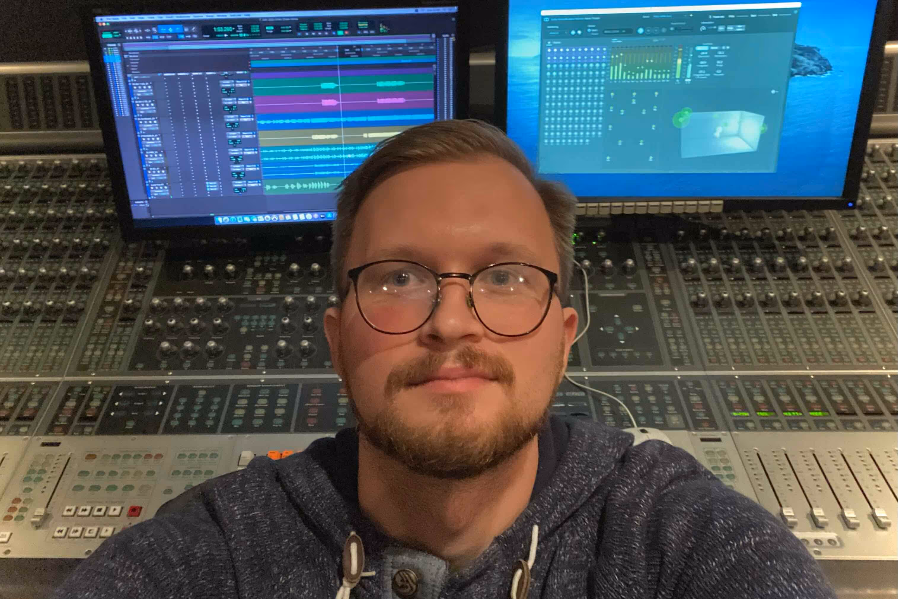 A personal photo of owner of GK Mixing with a mixing console behind him.