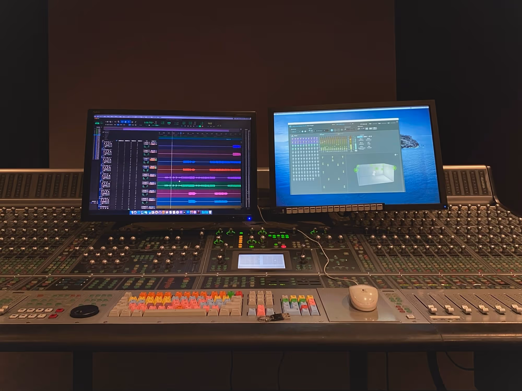 Close-up of a professional Dolby Atmos mixing console with dual monitors displaying a digital audio workstation (DAW) session and surround sound panning interface, showcasing a cutting-edge studio environment for high-quality music production and mixing.