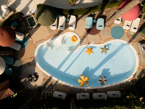 Aerial view of La Serena Hotel’s pool with colorful umbrellas, loungers, and playful floats.