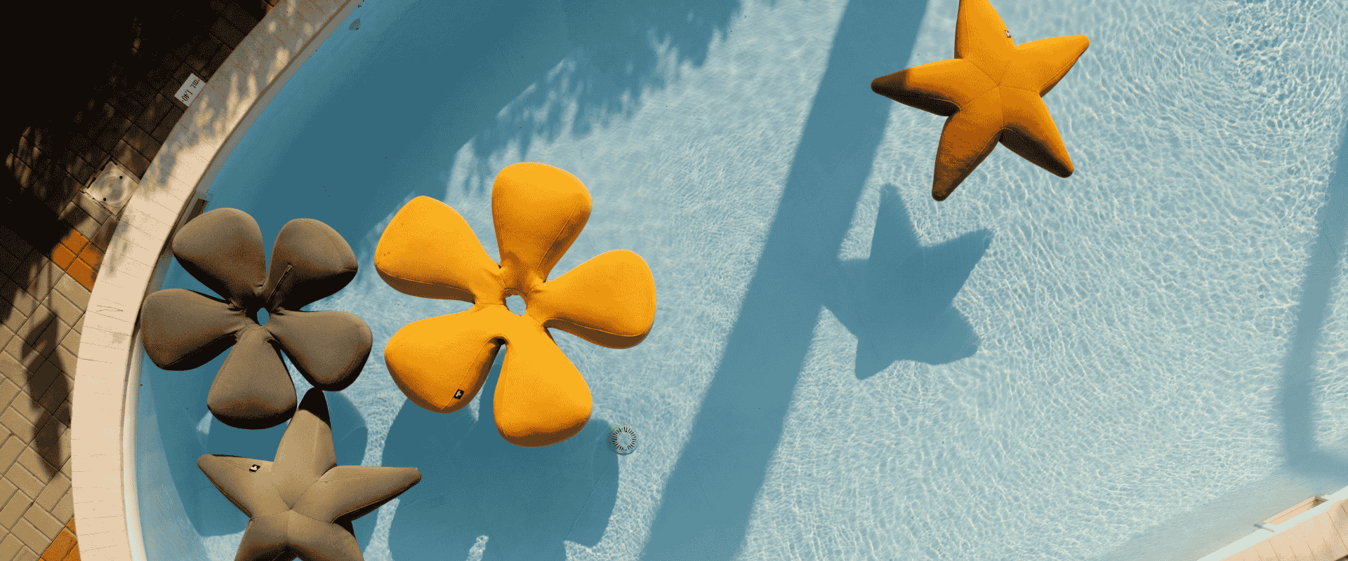 Decorative starfish and flower floats in a turquoise swimming pool seen from above