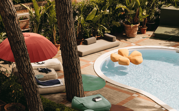 Hotel pool with lounge chairs and tropical plants in a sunny garden