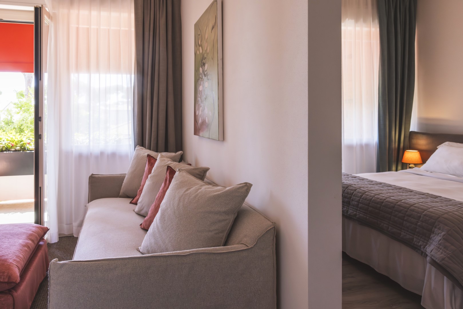 Hotel balcony attached to a family room, overlooking lush gardens and the pool.