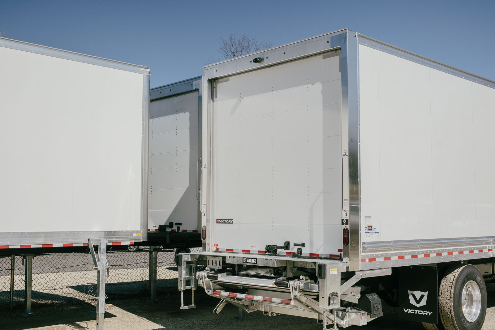 Multiple white Victory box trucks parked next to each other.