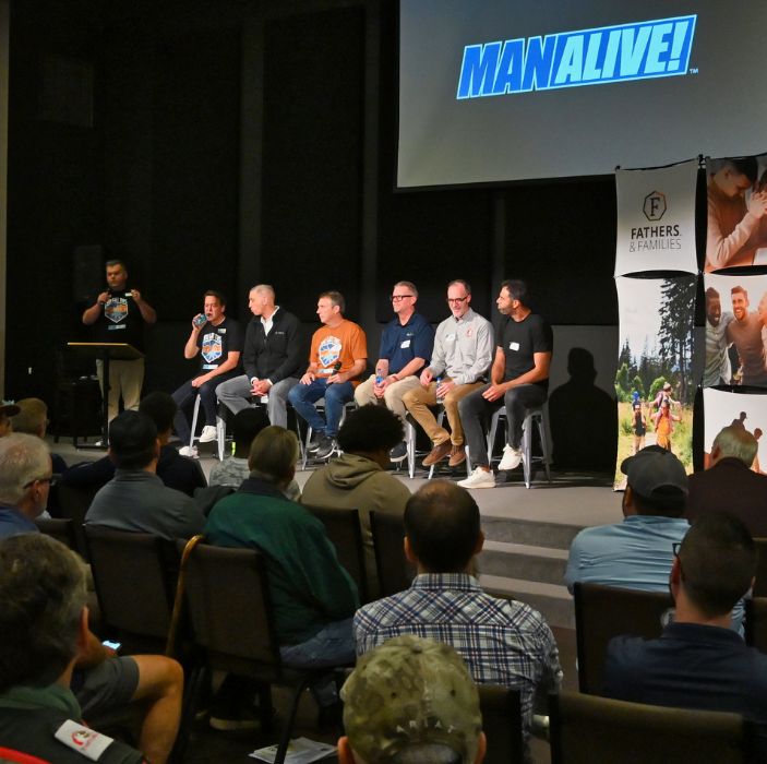ManAlive event photo of a panel of Christian leaders sitting on a stage in front of a gathering of men, sharing insights on how to lead as a father and a Christian man in their homes and communities.
