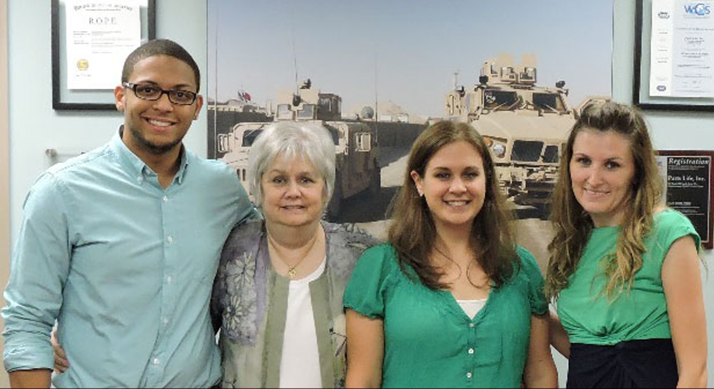 Isaiah is supported by four individuals standing beside him. From left to right: Chris Small, Meredee Parsons, Cecilia Lewin, and Jeannie Whitfield.