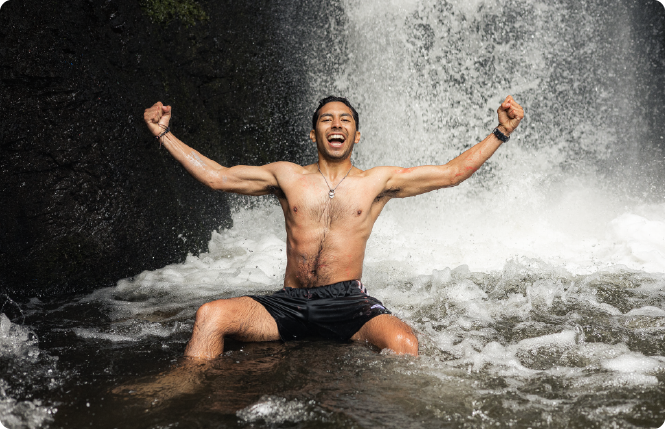 Man with gray hair and beard in navy suit and tie sitting with hands clasped, looking thoughtful.