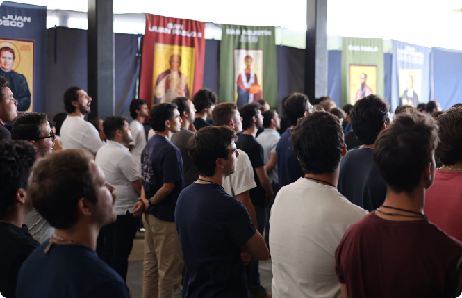 Man with gray hair and beard in navy suit and tie sitting with hands clasped, looking thoughtful.
