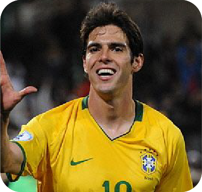 Smiling man with short brown hair wearing a dark jacket and blue shirt outdoors with blurred green foliage background.