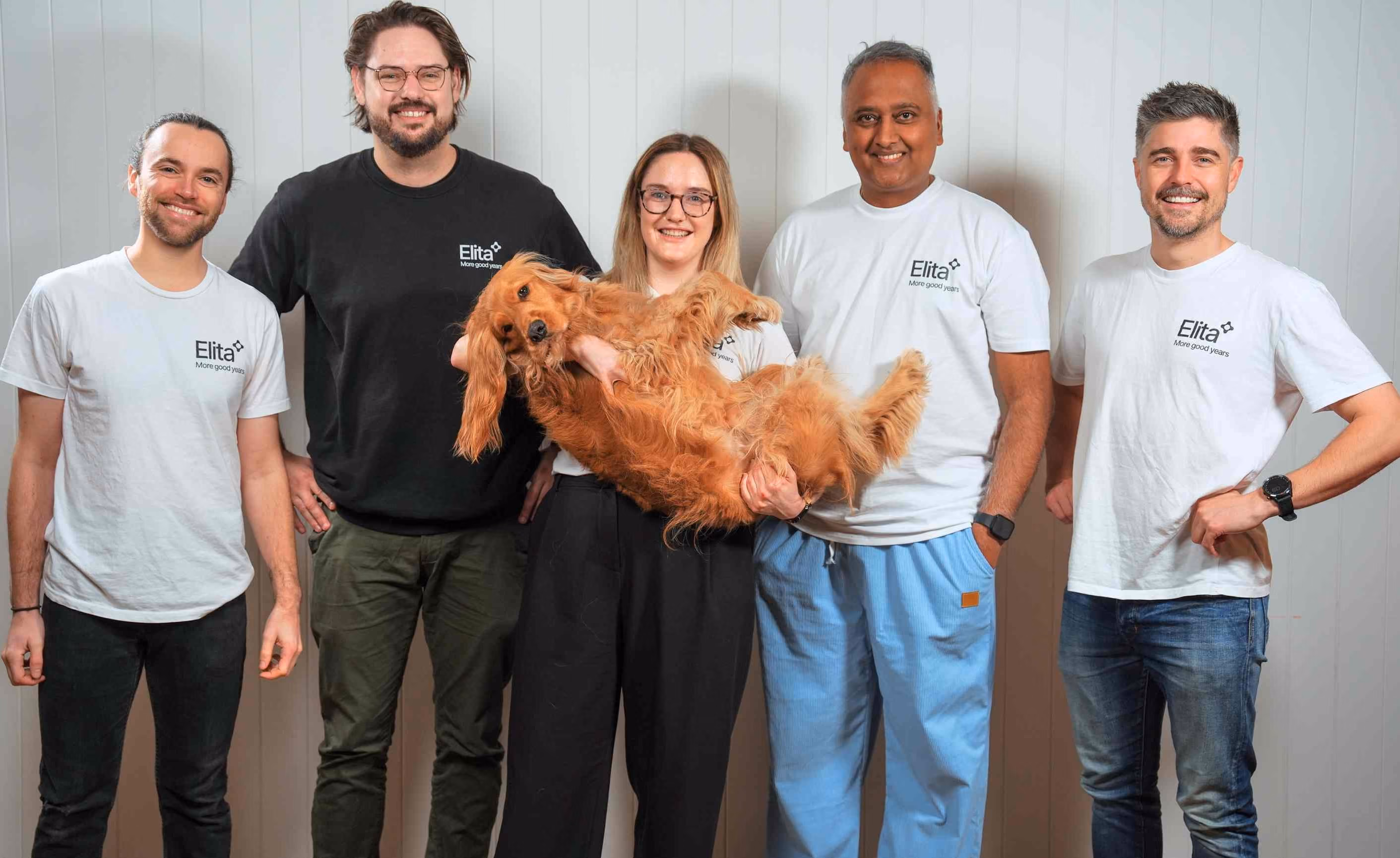 The Elita team holding a dog and laughing