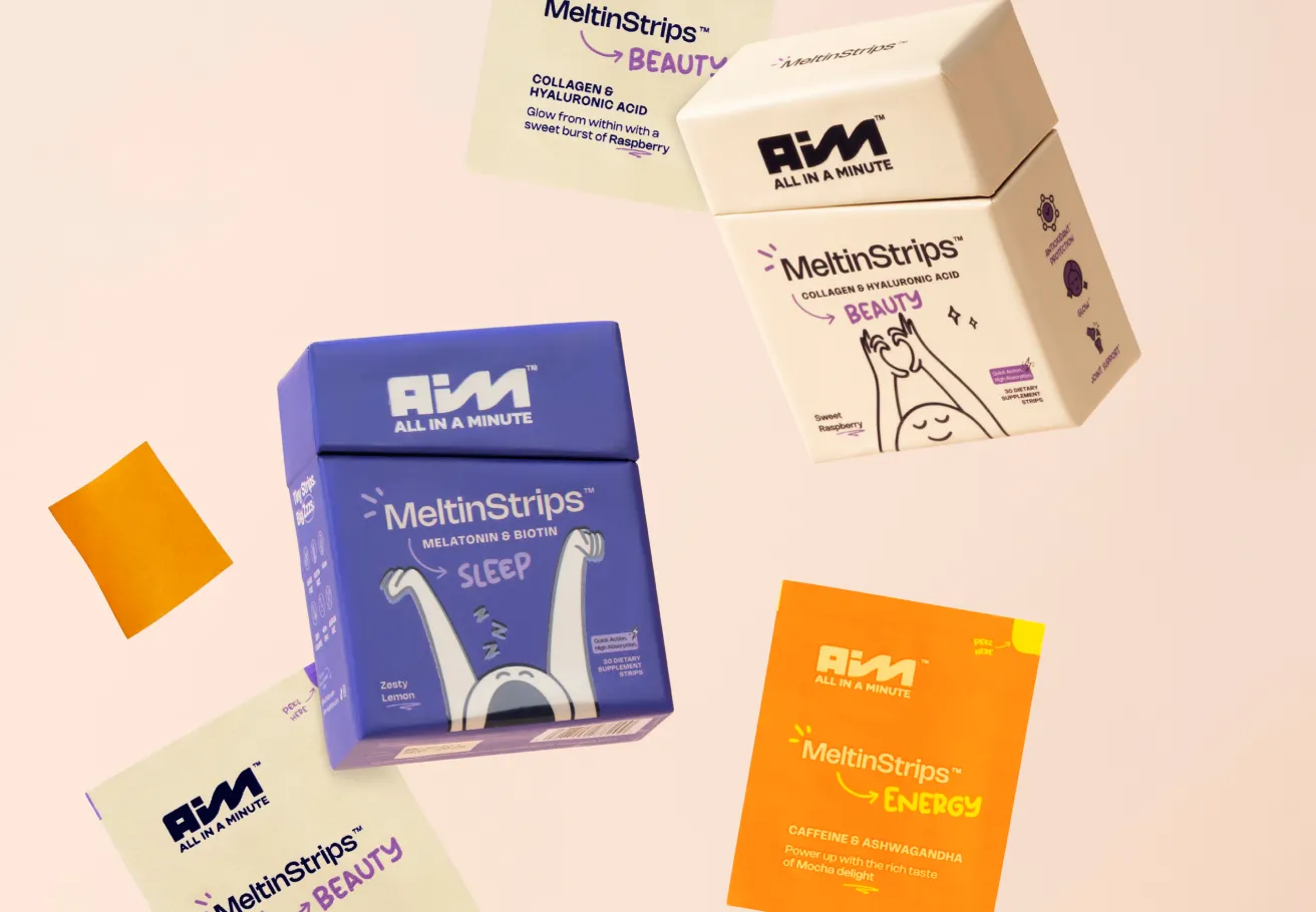 A flat lay photograph of several products from AIM Nutrition's 'MeltinStrips' line, including blue boxes for 'Sleep' and white boxes for 'Beauty,' along with small orange sachets for 'Energy,' all scattered on a light background